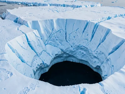Surface pool draining through blue ice