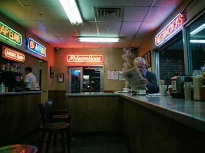 Old man reading newspaper at diner counter