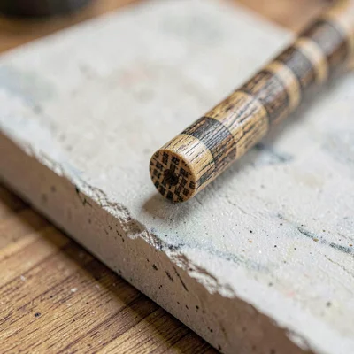 Worn-material closeup of an ash handle end with checkered grain on chalky board