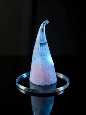 Ice spike with a slight curl at its tip, isolated on cold black glass, deep blue