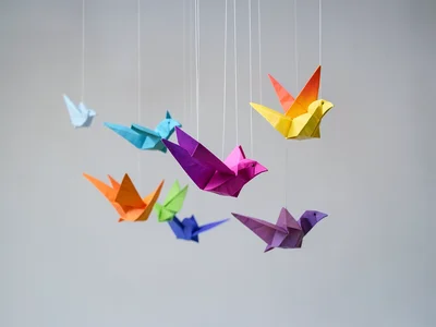 Origami bird flock in mid-flight, suspended by invisible threads, gradient paper