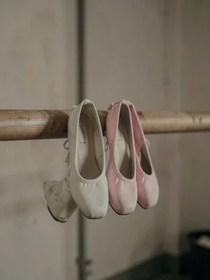 Ballet shoes hung on a barre, pink faded to almost white, a career's worth of we