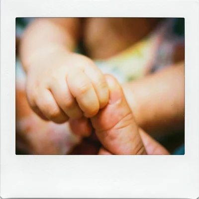 A baby's hand gripping an adult's finger, extreme close-up, soft focus, warm ton