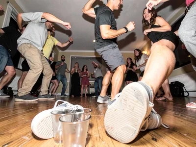 House party from floor level, solo cups and shoes distorted massive in foregroun