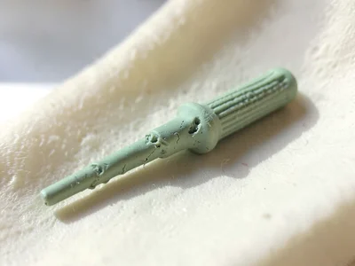 Knurled sage-green screwdriver with a slumped handle grip and fingernail dents a