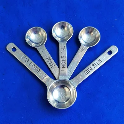 small aluminum measuring spoon set fanned out top-down on a saturated cobalt bac