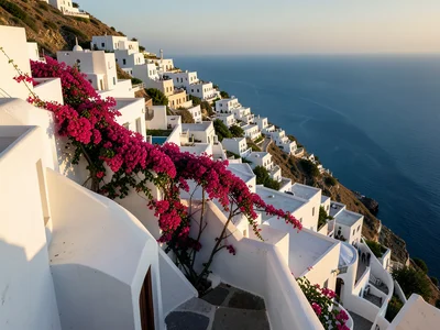 Whitewashed Greek village cascading down a hillside to blue sea, bougainvillea s