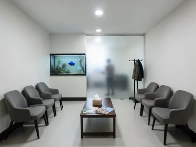 An empty dentist's waiting room with six upholstered chairs along two walls, a l