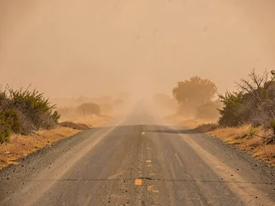 Road disappearing into dust haze thirty meters ahead