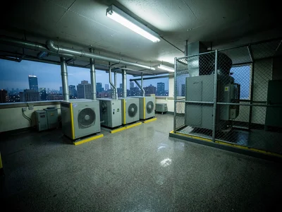 A rooftop mechanical room of an office building, grey industrial equipment — HVA