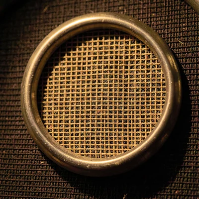 Mineral close-up of a tube amp grille cloth with woven fibers haloed by lampligh