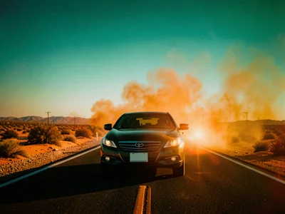 A car on a desert highway at dusk, teal sky gradient above, orange dust cloud be