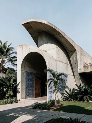 Modernist chapel with parabolic roofline, single palm silhouetted beside the ent
