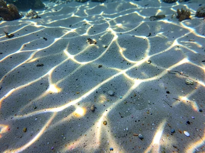Light focus points creating bright dots across underwater sand
