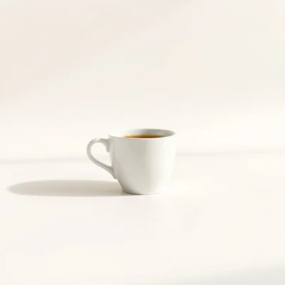Minimalist studio photograph of a single white coffee cup on a clean matte surface, centered composition, soft diffused 