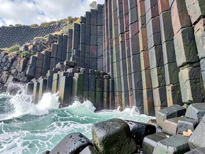 Wave crashing against columnar basalt cliff