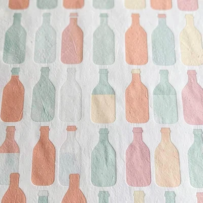Papercraft pattern of repeating paper-cut ink bottles in soft sage, coral and bu