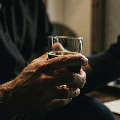 Moody close-up of a hand cradling a tumbler, deep shadow palette