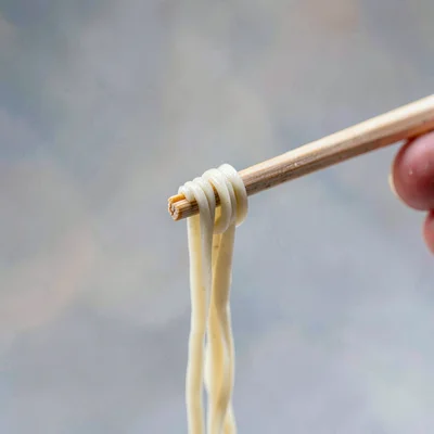 Macro 4:5 of a single chopstick lifting a strand of noodle