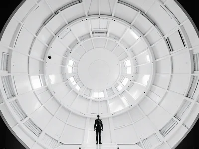 Circular space station interior, white, symmetrical, figure standing at center b