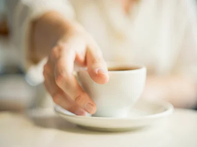 Hand reaching for coffee cup, background dissolved
