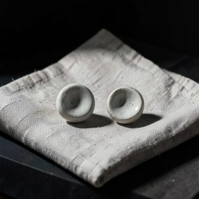 Pair of handmade ceramic earrings on a linen cloth, artisan jewelry display
