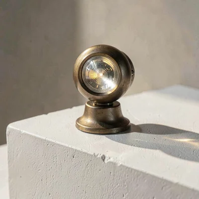 Sculptural mineralcut closeup of a moving-head fixture on a chalky white plinth,