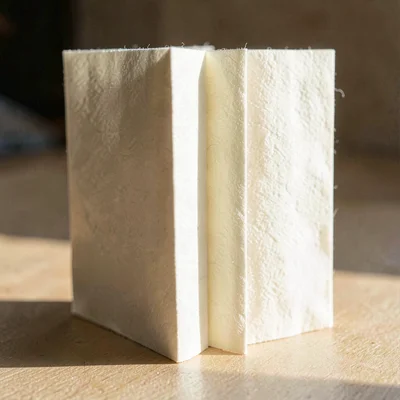 Cream cotton paper folded into a slim accordion menu standing on its spine, raki