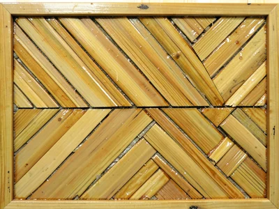 A chevron border detail on a straw-inlaid frame, lacquered ground visible betwee
