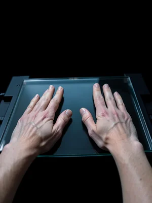 Two hands pressed palm-down on the scanner bed, fingers spread, skin texture imp