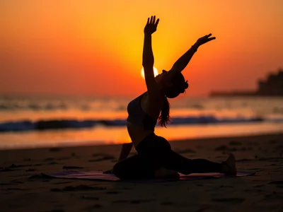 Person doing yoga on a beach at sunrise, silhouette against the orange sky