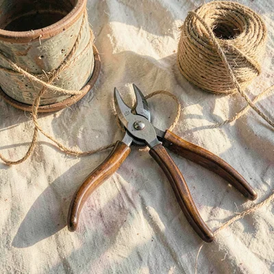 Warm flatlay of pruning shears, twine and a pot on a sunlit linen, late afternoo