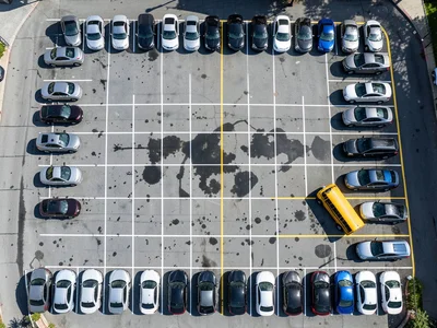 A church parking lot on Sunday morning from above, 90% full, nearly every vehicl