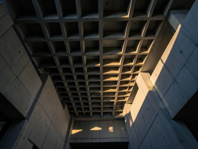 A waffle-slab ceiling in a brutalist building, the geometric grid creating a che