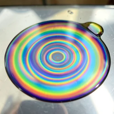 Motor oil drip on chrome surface, rainbow thin film spreading in concentric ring