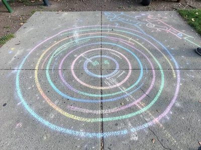 A massive chalk labyrinth on a playground, the concentric paths visible from abo