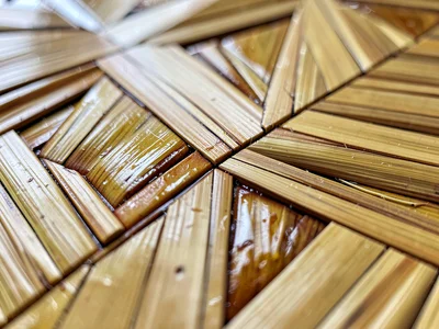 Close-up of a straw marquetry surface at extreme raking angle — texture and refl