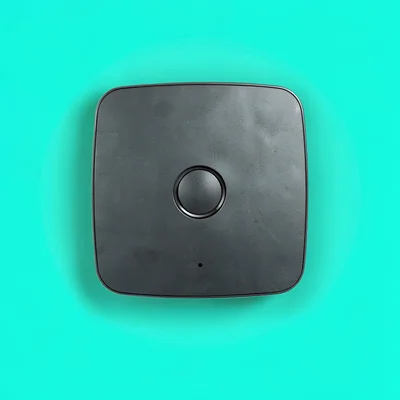 single matte-charcoal smart-thermostat puck straight-on against a saturated mint
