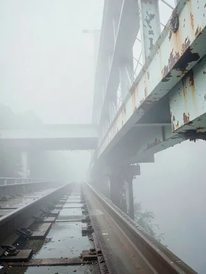 Rail bridge with chipped paint girders, sleepers wet, the further span reduced t