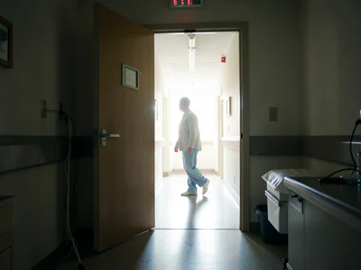 A hospital room door opening to a blindingly bright hallway, a figure half-throu