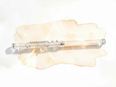 Crystal-clear lowpoly flute laid horizontally with a slim transparent body catch