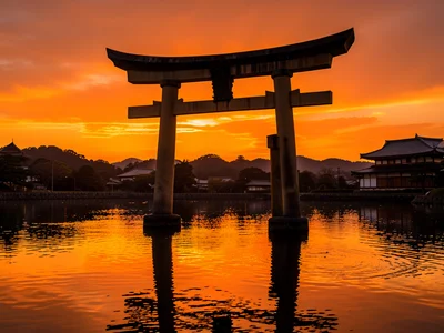 Traditional Japanese torii gate standing in water at sunset, orange sky reflecte