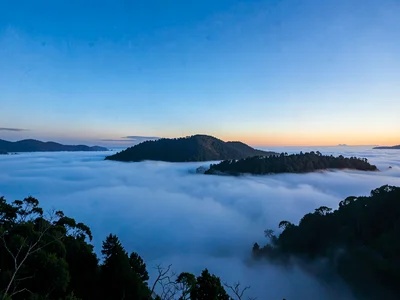 Valley fog below with hilltop island emerging into clear blue