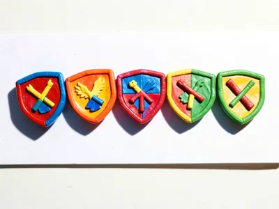 Row of seven chunky clay shields with varied primary-color heraldry arranged in