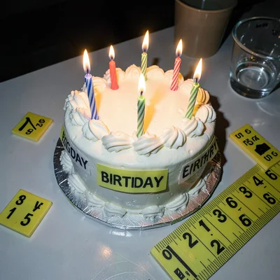 Birthday cake with lit candles documented with evidence markers and measuring ru