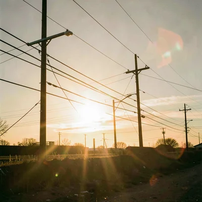 Power lines and utility poles backlit by setting sun