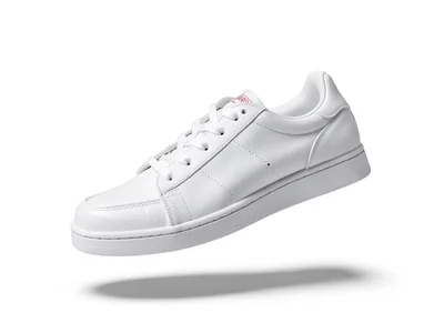 Single white sneaker floating on white seamless, shadow beneath it the only grou