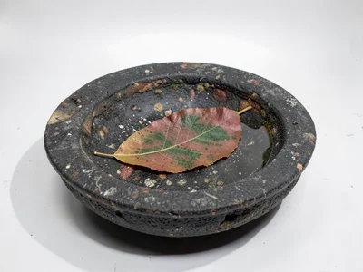 A single leaf floating in a stone basin, ninety percent negative space