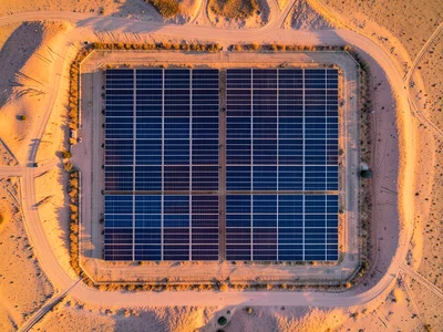 A solar farm from above, the panels creating a blue-black geometric grid, desert