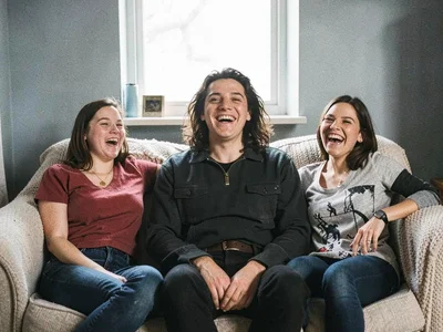 Three friends cramped into frame on a couch, person in middle distorted large, t